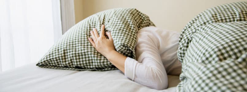 woman covering her head with a pillow