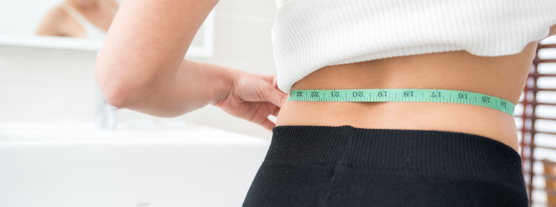 thin woman measuring her waist