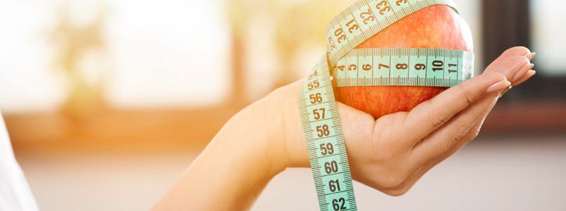 woman holding an apple that is wrapped in a measuring tape