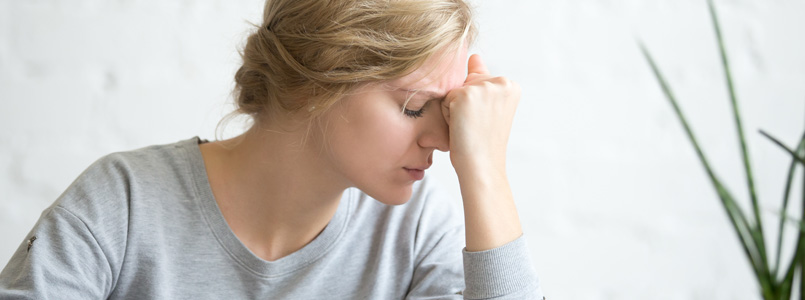 woman with her forehead pressed into her fist experiencing Acxion side effects